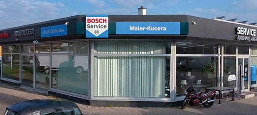 Ein Geb udefront mit den Schildern Citro n, D HER KUCERA und Bosch Car Service unter einem bew lkten Himmel. Beschreibung von KI generiert